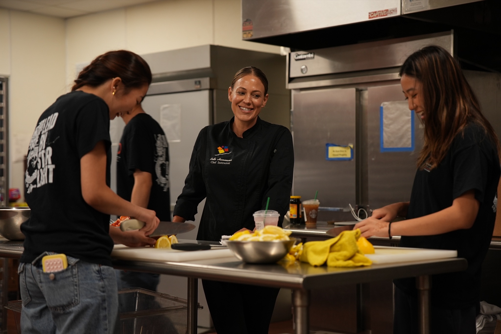 Chef instructor smiling with Food for Thought volunteers in the kitchen